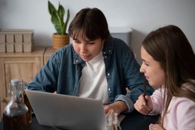 A parent sitting next to a teenager, both looking attentively at a laptop screen. The parent is pointing at something on the screen, indicating a discussion is taking place.